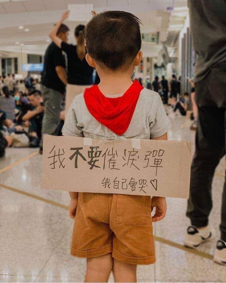各大社群網站近日廣傳1張照片，1名幼童於香港機場反送中靜坐行動現場，背上貼有「我不要催淚彈，我自己會哭」標語牌。 圖：翻攝自微博