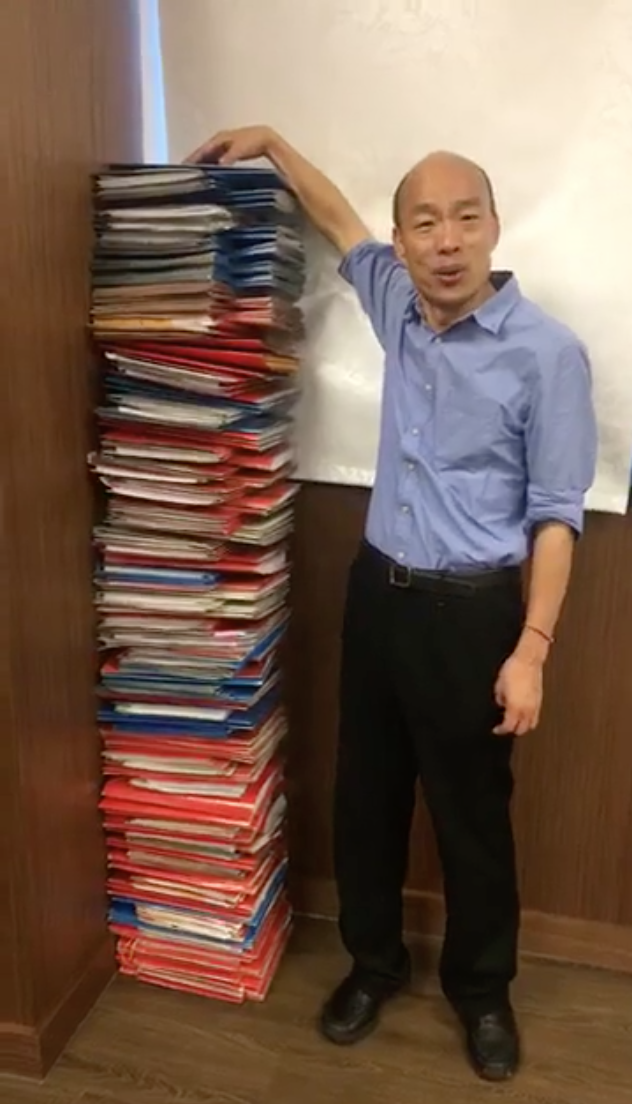 韓國瑜日前在臉書開直播，將一大批公文疊在一旁，強調自己的批示的公文量也跟他一樣高。 圖：翻攝自韓國瑜臉書