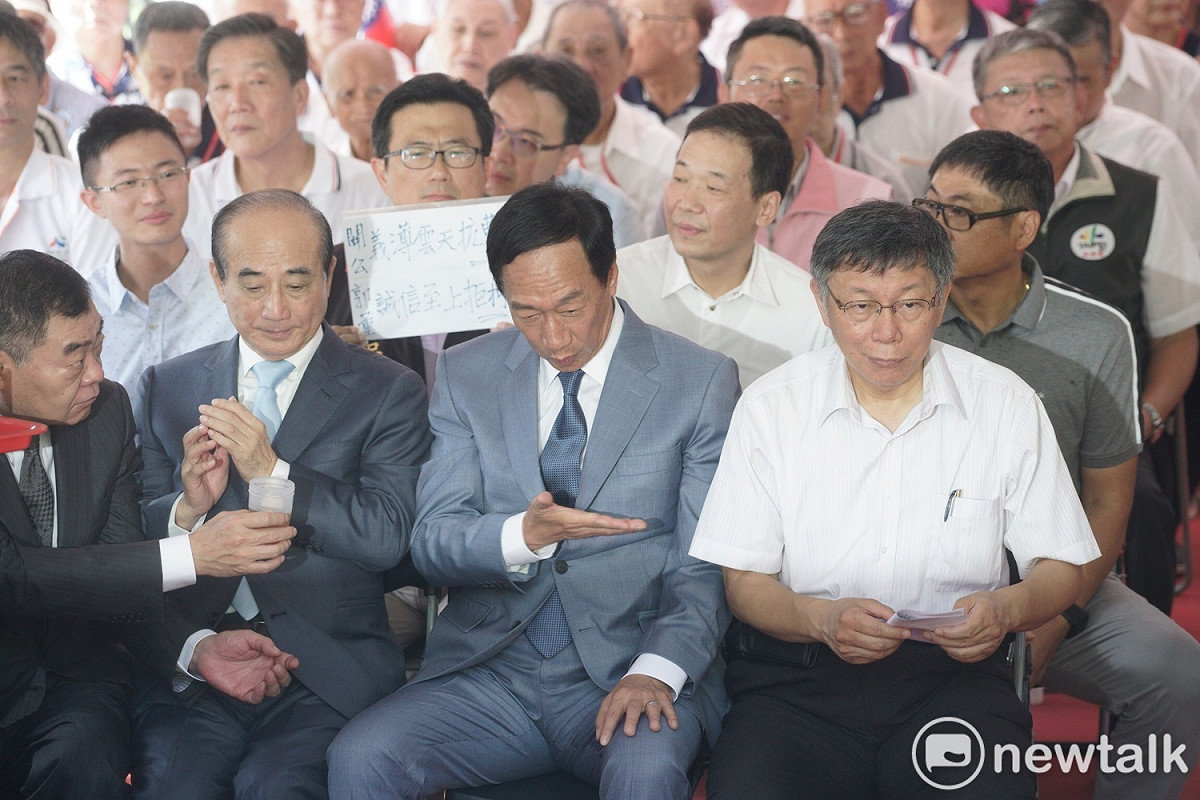 坐在郭、王、柯背後的國民黨議員吳世正高舉著「關公義薄雲天抗曹營，郭董誠信至上拒柯Ｐ」的標語，籲郭王拒絕和柯合作。 圖：張良一 / 攝