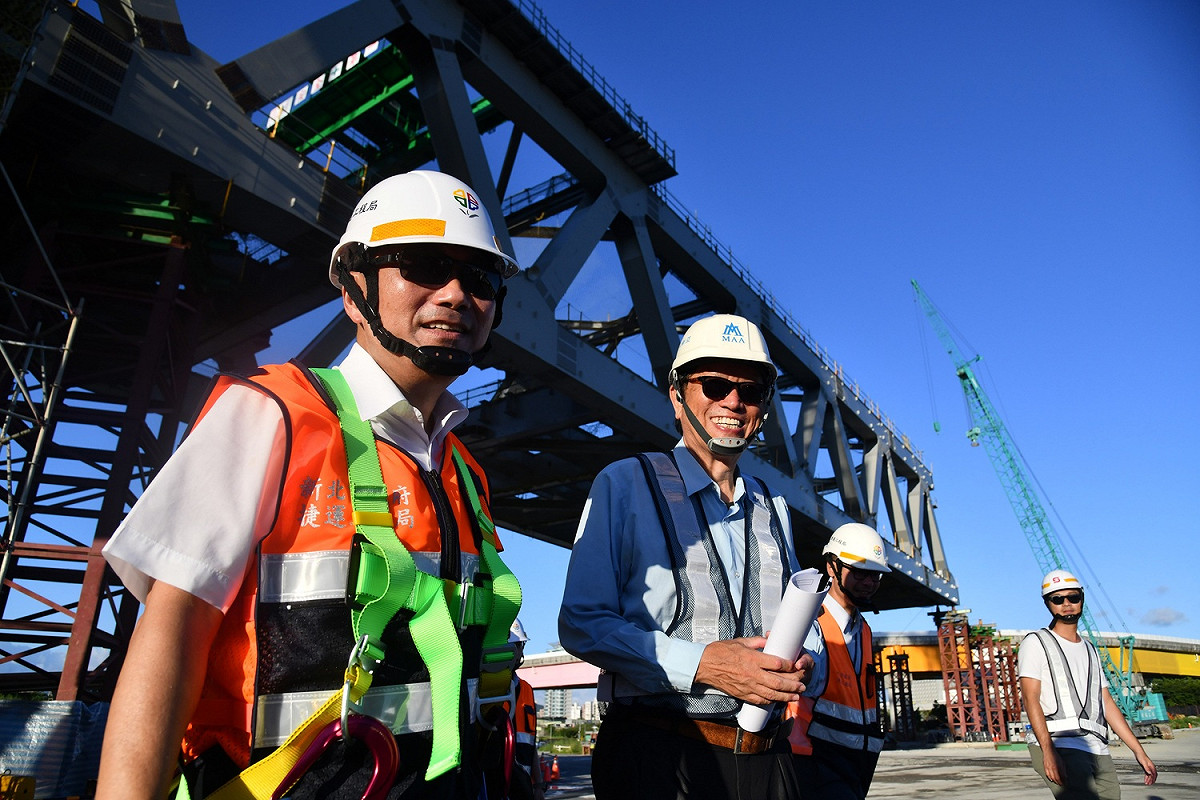 新北市長侯友宜穿戴安全配備擔任「一日工頭」，實際了解安坑輕軌工程中安心橋橋體鋼桁架吊裝作業。 圖：新北市政府捷運局／提供