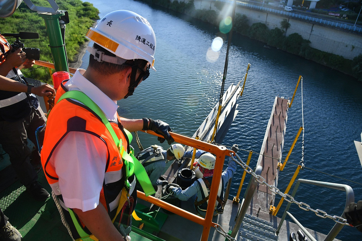 新北市長侯友宜穿戴安全配備擔任「一日工頭」，實際了解安坑輕軌工程中安心橋橋體鋼桁架吊裝作業。 圖：新北市政府捷運局／提供