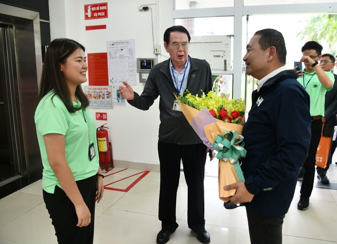 侯友宜由儒鴻企業董事長洪鎮海(中)陪同參觀越南同奈省的仁澤成衣廠，台灣新住民第二代廠長Rita獻花歡迎。 圖：新北市政府提供人