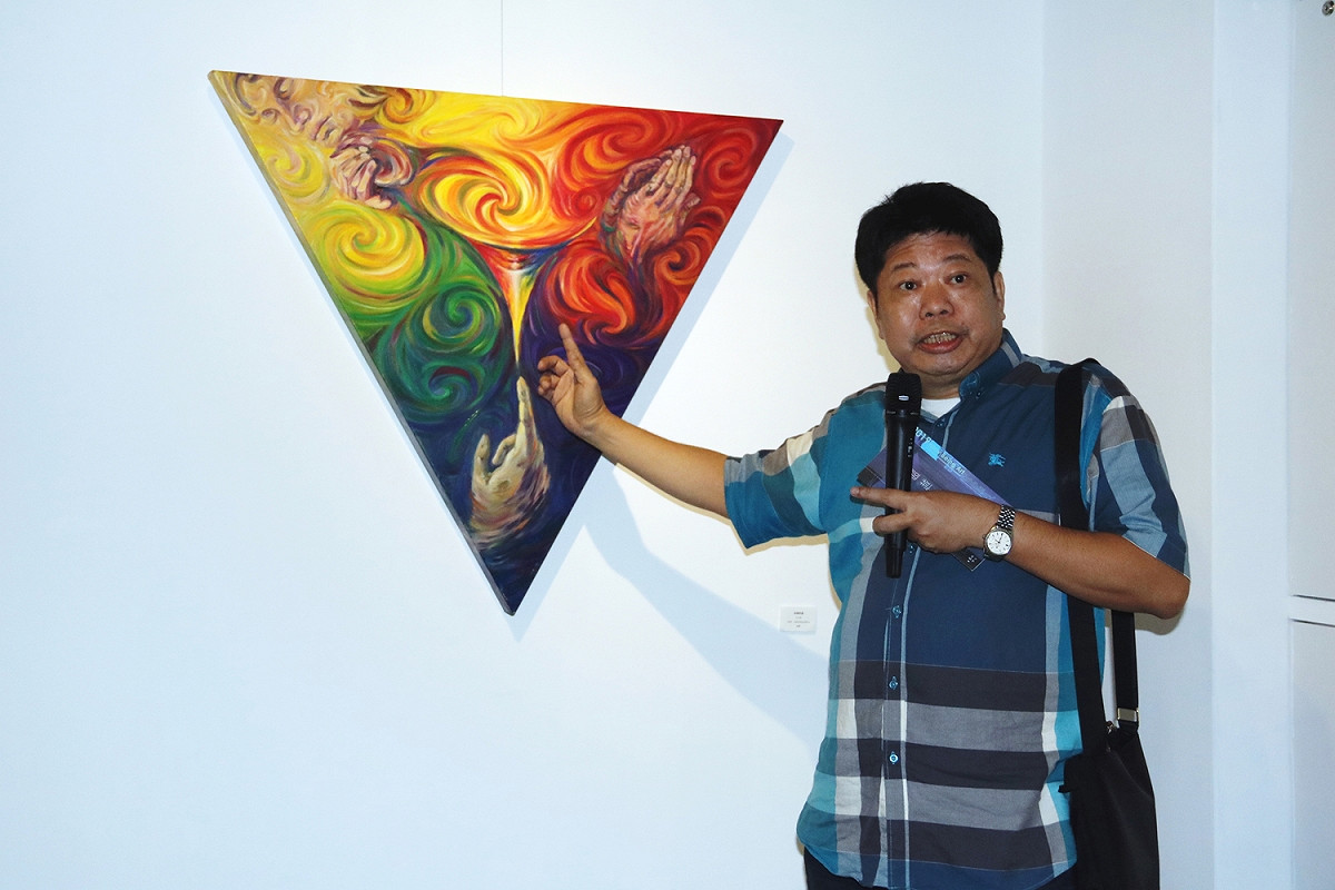 策展人王以亮解說他參展的三角形油畫「終極盼望」。 弘光科大/提供