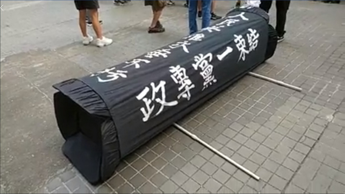 香港社會民主連線今早在灣仔發動黑衣遊行，還帶了一副「道具棺材」，遭大批黑社會襲擊，並暴力將道具棺材摧毀。 圖：翻攝社會民主連線