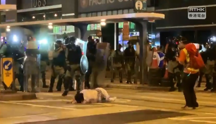 一名身穿類似和服的市民，站在警方防線前，被警員推跌地上。 圖：翻攝RTHK NEWS臉書影片