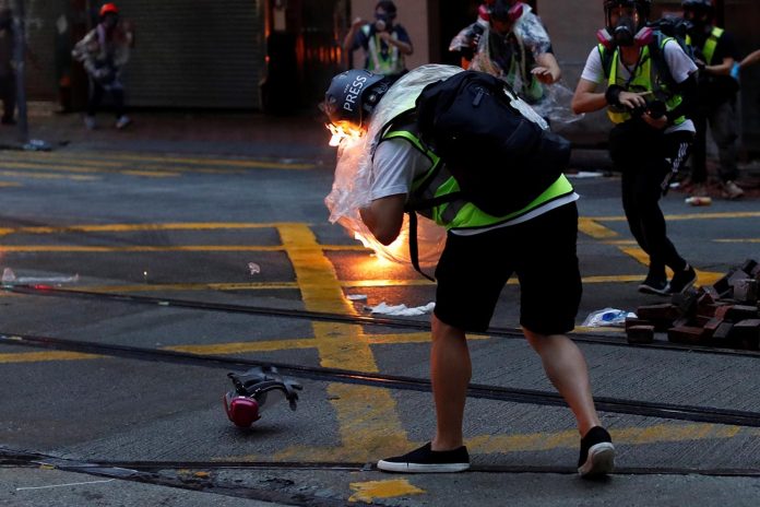 香港示威者與警方爆發激烈衝突，有多名記者被汽油彈擊中，一名香港電台記者雨衣着火，傷及耳朵。 圖：翻攝香港01