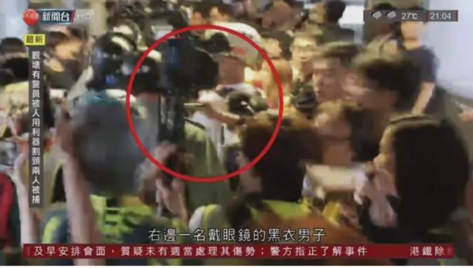 黑衣男子自人群中伸出利器，朝警員的後頸劃了一刀 圖：翻攝自電視台畫面