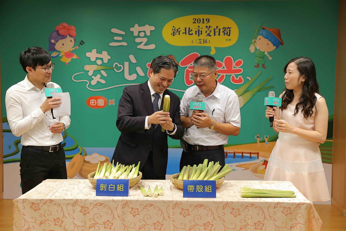三芝農會總幹事郭錦炎 (右二)向副市長吳明機介紹如何挑選茭白筍。 圖：新北市農業局／提供