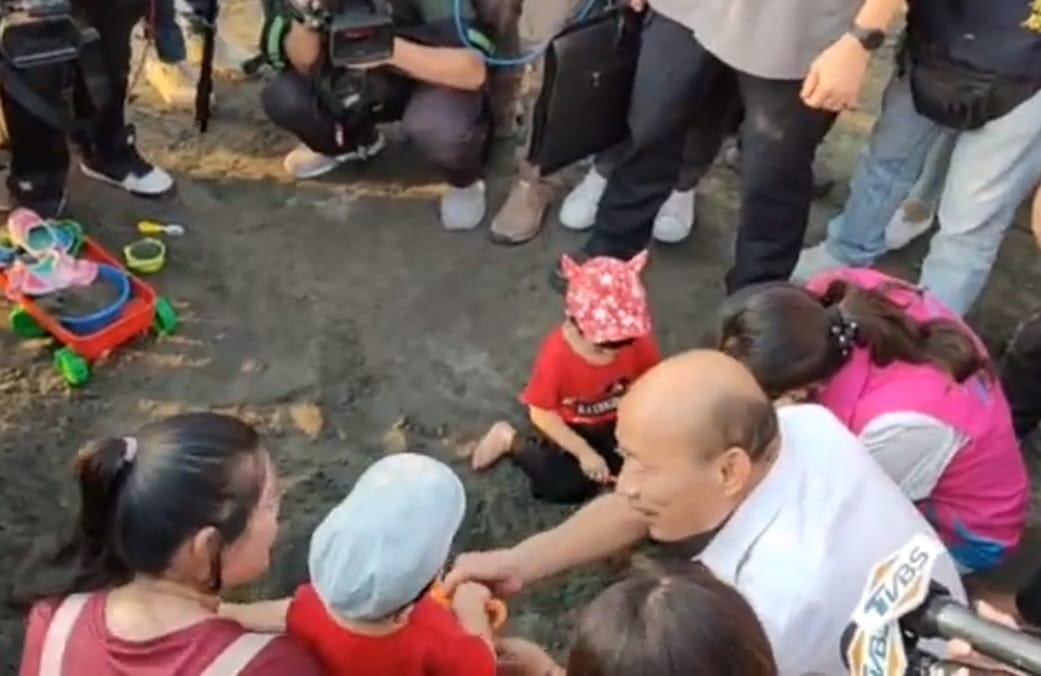 韓國瑜原直接要拿走小男童手中的沙鏟，不料，男童手抓得很緊，不給就是不給。 圖:翻攝自土包子志工團臉書