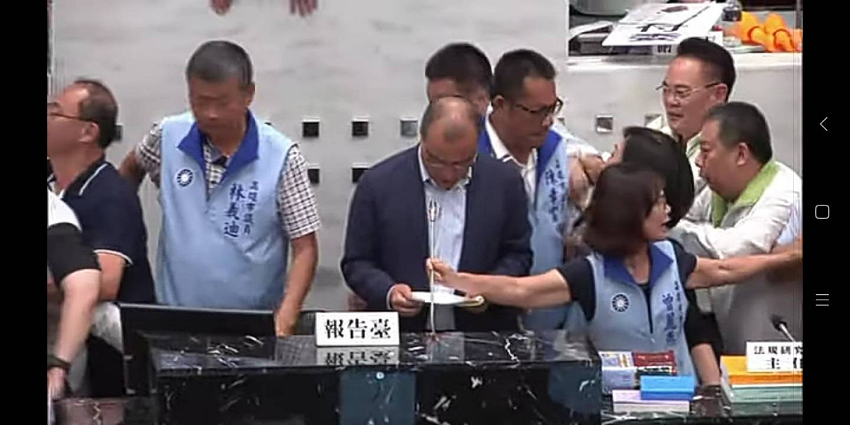 在國民黨籍議員的護衛下，葉匡時於混亂中上台報告。 圖 : 孫家銘/攝