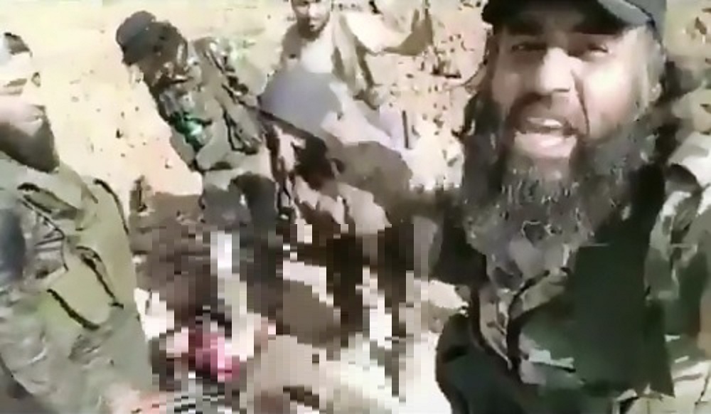 1名自稱是敍利亞「榮耀兵團」聖戰士的大鬍子士兵自拍，拍下同袍踐踏庫德族女兵屍體畫面，國際震怒。 圖：翻攝自 Karo Alany臉書影片畫面