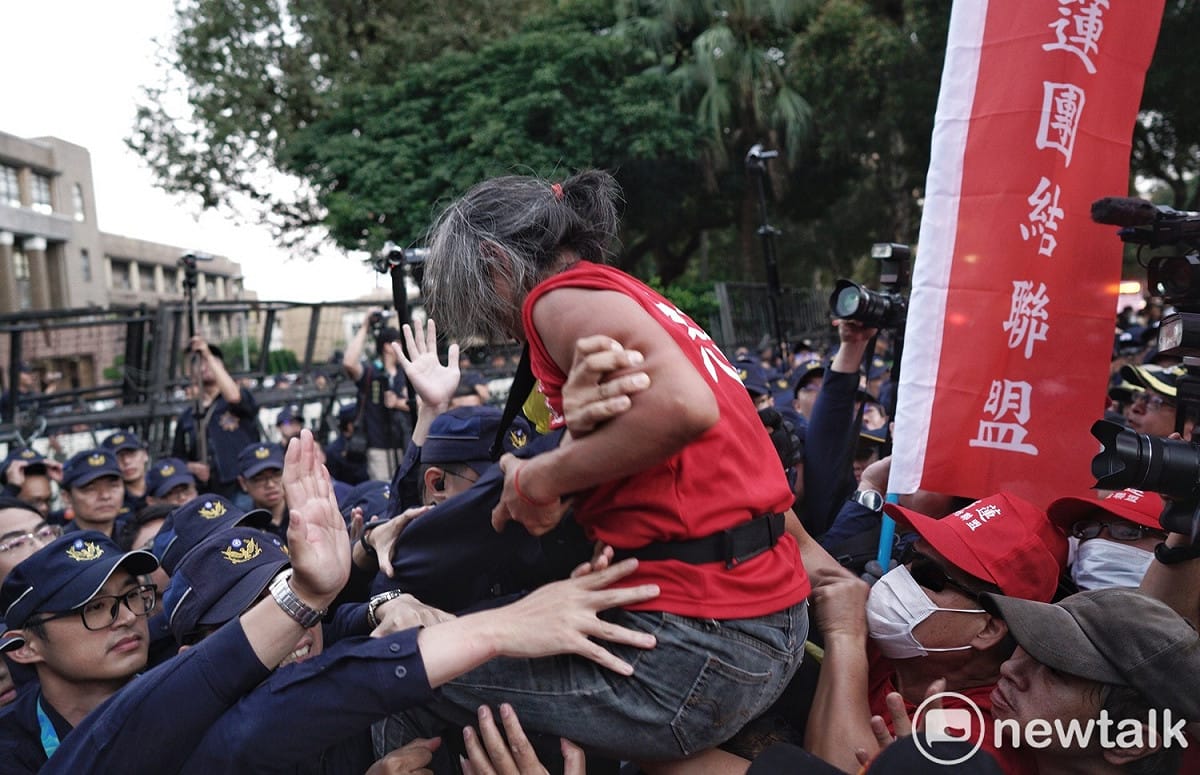 一名紅衣男子試圖越過拒馬、進入行政院，遭警方攔阻。 圖：張良一／攝