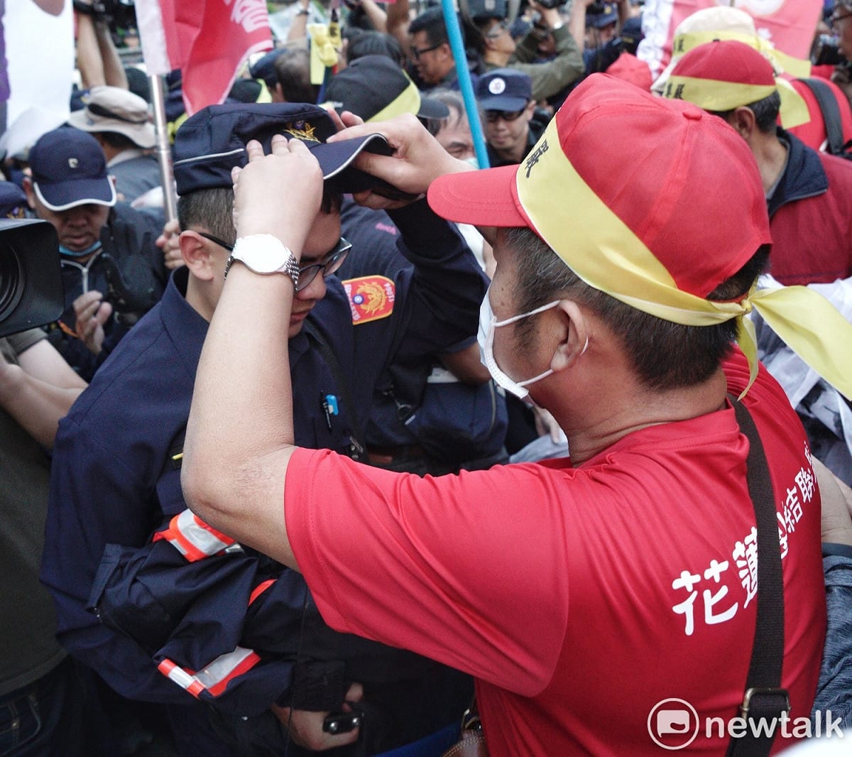 一位退警在衝突中幫一位現役警察戴好帽子。 圖：張良一／攝