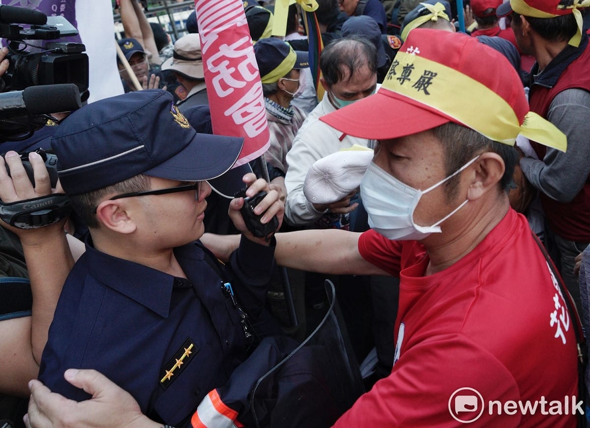 一位退警在衝突中幫一位現役警察戴好帽子，並拍肩為現役警員打氣。 圖：張良一／攝