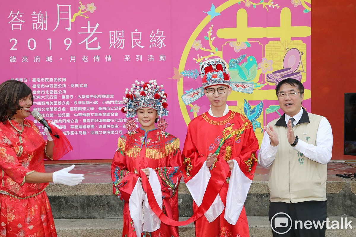 台南市長黃偉哲出席祀典武廟舉行的新人「答謝月老賜良緣」記者會，由反串媒人婆邱賢珉帶領北區新郎「百年」及中西區新娘「好合」進行答謝月老的儀式，並由市長扮演好命公，為百年先生和好合小姐牽起幸福的紅線，啟動「緣來府城．月老傳情」系列活動。 圖：黃博郎／攝