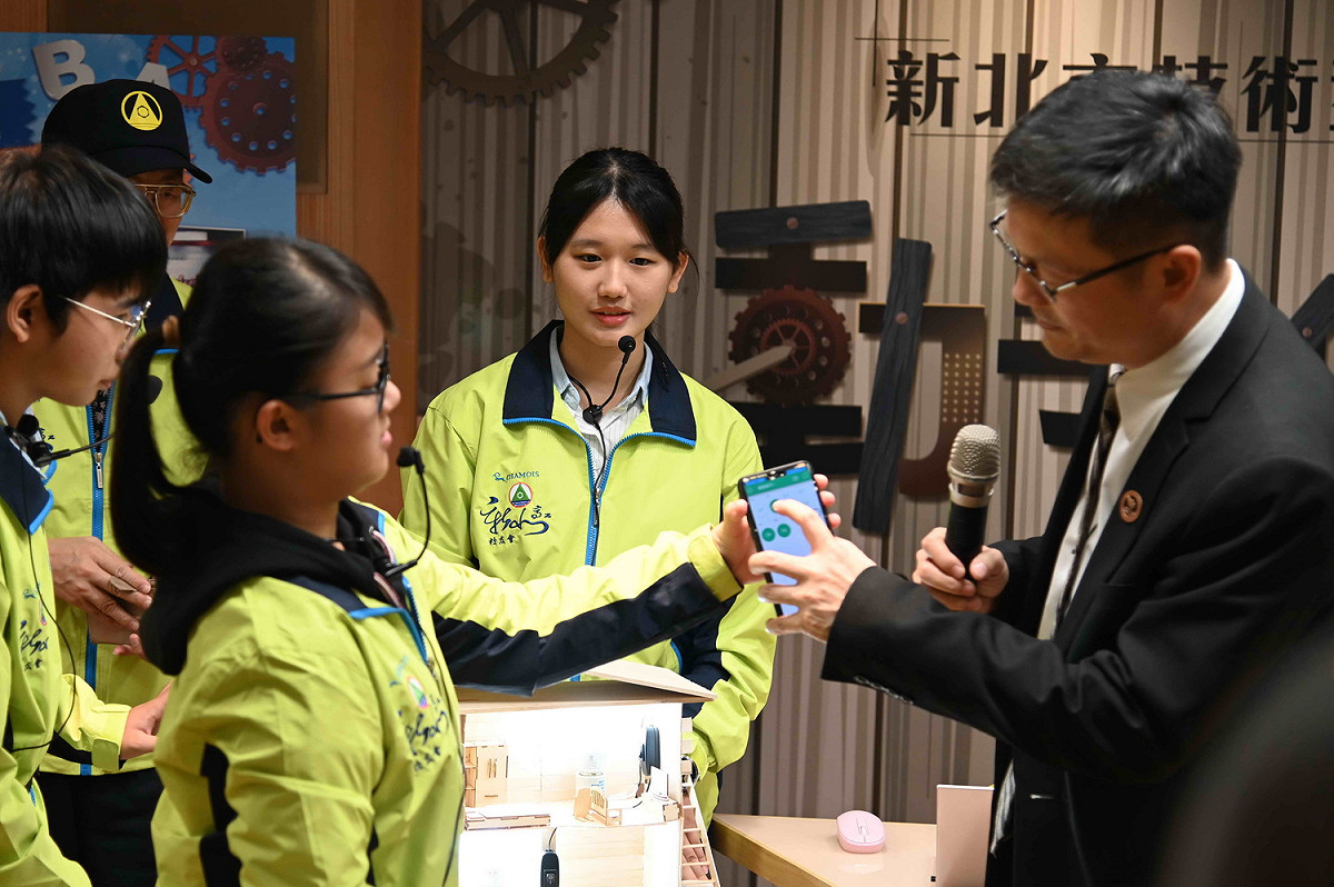 教育局長張明文與學生用英文討論「智慧雲端居家節能監控系統」的設計。 圖：新北市教育局提供