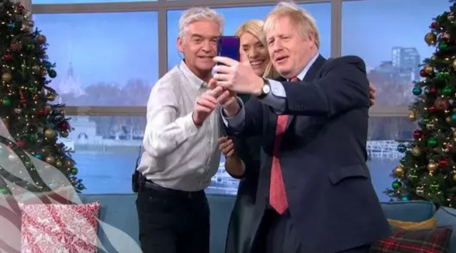 英國首相強生(Boris Johnson)(右一)持華為手機和主持人合照。 圖：翻攝自微信