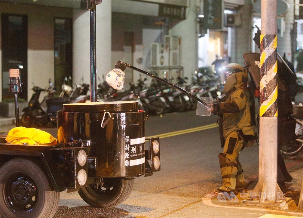 警方追查涉嫌在國民黨台南市後壁區黨部大門旁放置不明物體的男子，13日循線在高雄市苓雅區永樂街一棟大樓包抄攻堅，雙方對峙，犯嫌一度丟出一罐疑裝有不明液體的寶特瓶，防爆小組全副武裝，夾取寶特瓶。 圖/中央社