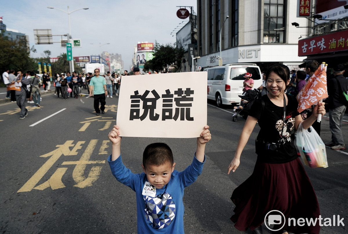 年幼孩童高舉大幅的「說謊」看板，兩者形成強烈對比。 圖：張良一/攝