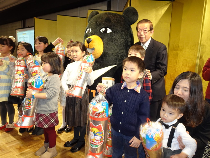 駐日代表處23日晚間在東京雅敘園舉辦尾牙，代表處員工攜家帶眷參加，謝長廷上台發耶誕禮物給孩童，氣氛和樂。 圖：中央社提供