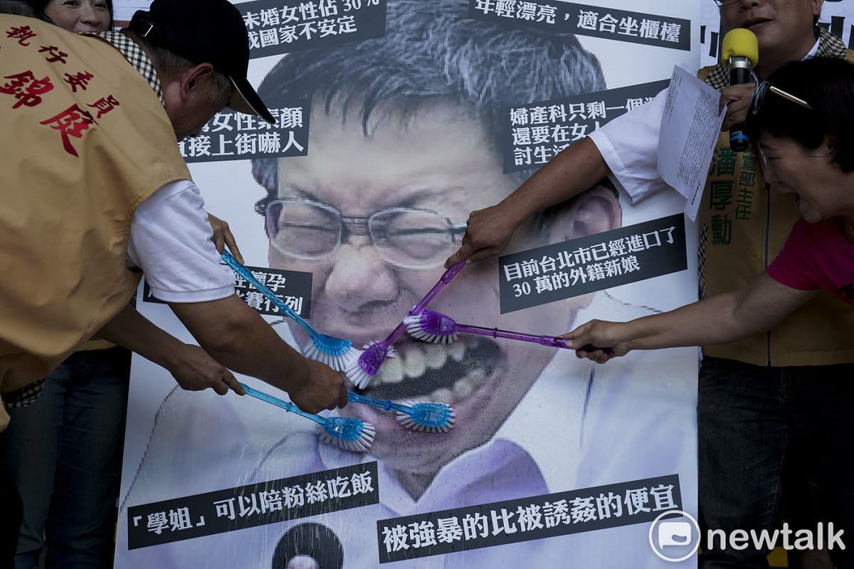 台灣團結聯盟成員在台北市政府前舉行的「請柯文哲管好市政、管好嘴巴」記者會中，用刷子刷柯文哲圖像中牙齒，藉此抗議柯文哲物化女性的諸多言論。 圖：張良一 /攝