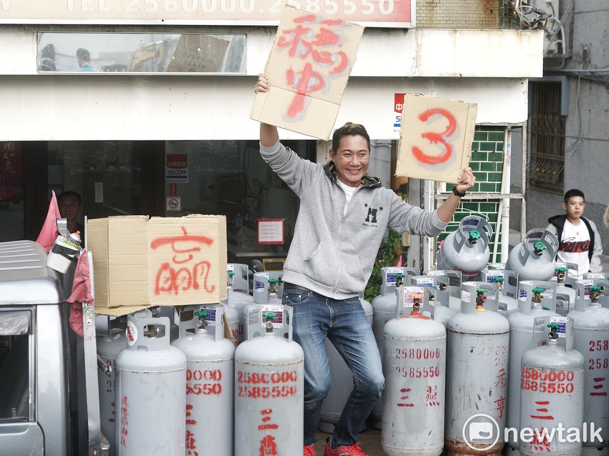 瓦斯行員工站在貨車上揮舞「3」和「穩中」紙牌。 圖：張良一 / 攝