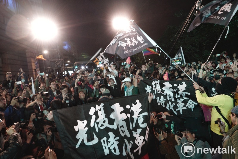 數十位在小英競總外見證台灣民主自由的香港人在現場揮舞或是高舉「光復香港時代革命」旗幟後，並以不曝光方式比出五大訴求手勢。 圖：張良一/攝