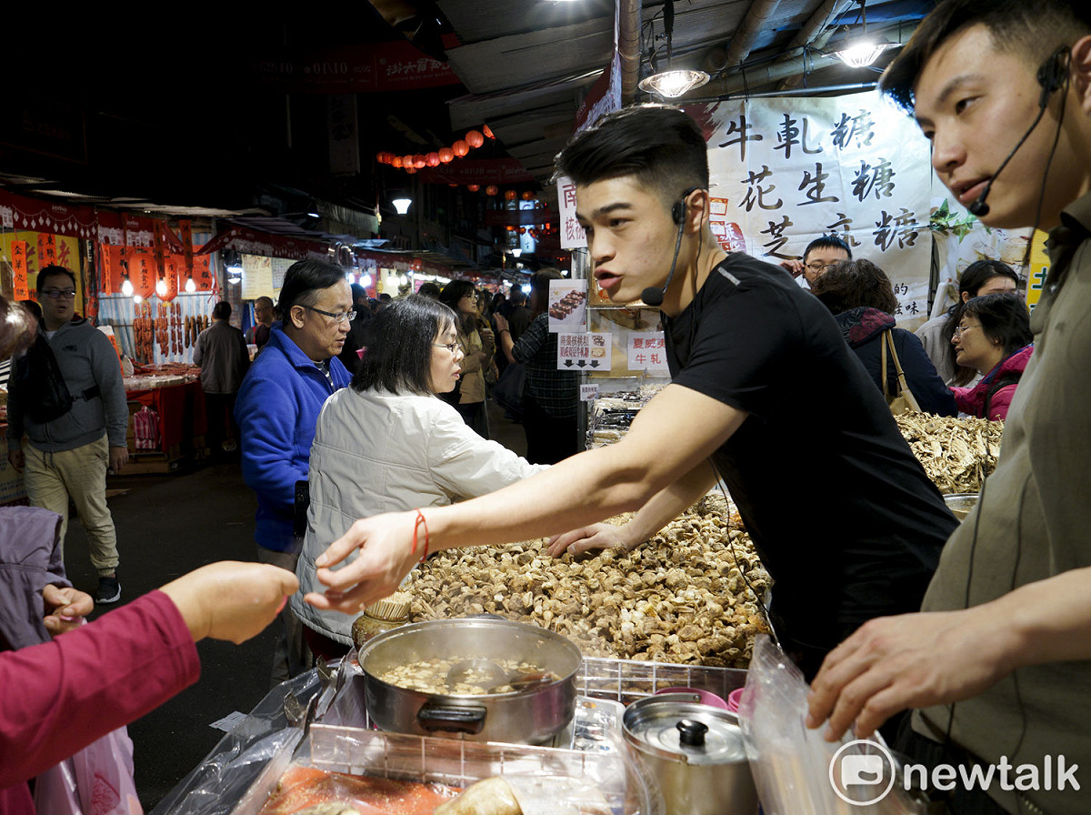 年輕的店員賣力的吆喝辦年貨的民眾試吃看看。 圖：張良一/攝