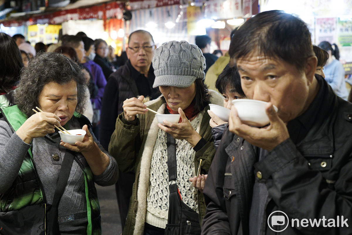 逛年貨大街的民眾試吃產品。 圖：張良一/攝