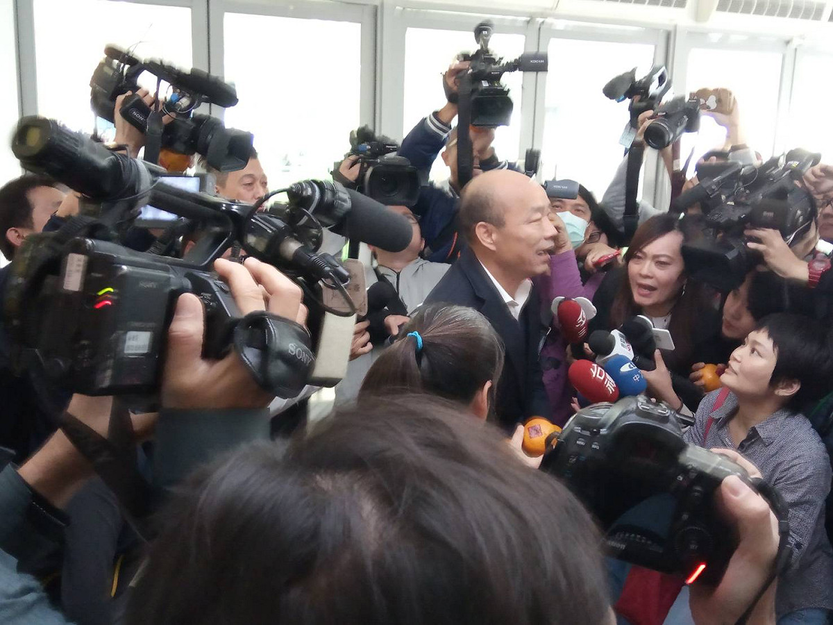 高雄市長韓國瑜(中)主持市政會議前，分送在場記者橘子。 圖：孫家銘/攝