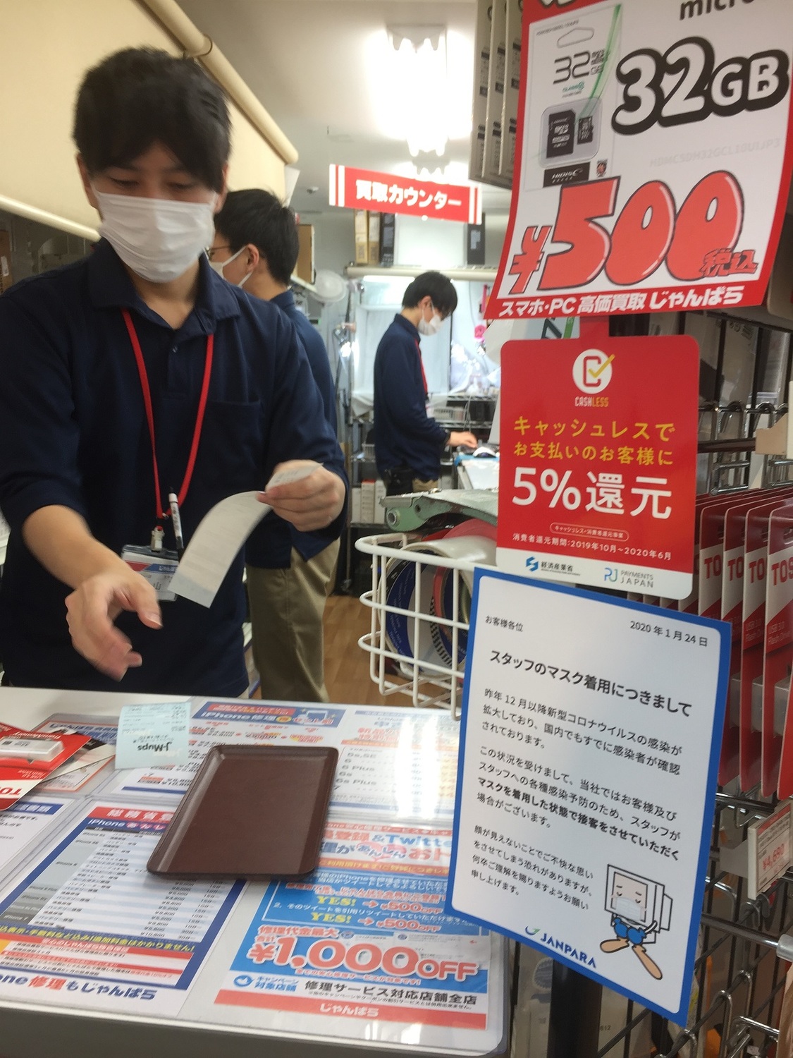 東京家電店店員被要求戴口罩接客，也貼出是因為武漢肺炎的說明。 圖：劉黎兒／攝