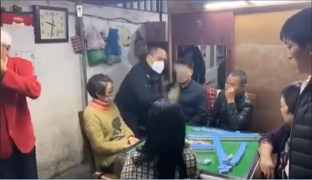 網路流傳影片大陸有人不顧防疫禁令，聚集打麻將遭公安查獲，戴著口罩的公安拿鐵鎚怒砸麻將桌。 圖：網路影片截圖