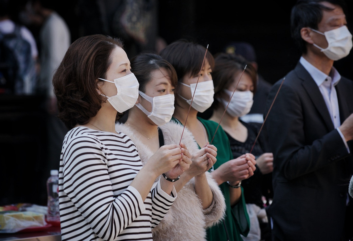 來自日本的觀光客戴上口罩向艋舺龍山寺的觀音佛祖獻上一柱馨香。 圖：張良一/攝