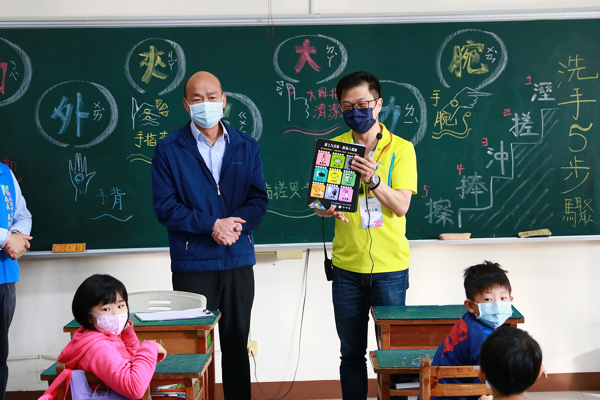 韓國瑜(左)致贈校方設計的「防疫墊板」給小朋友當開學禮。 圖：高雄市政府/提供
