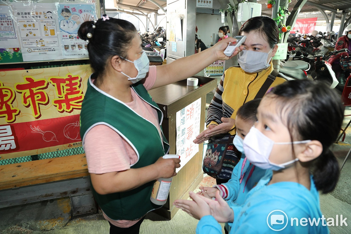 市場人員為攤商和顧客測量額溫，落實防疫工作。 圖：黃博郎／攝