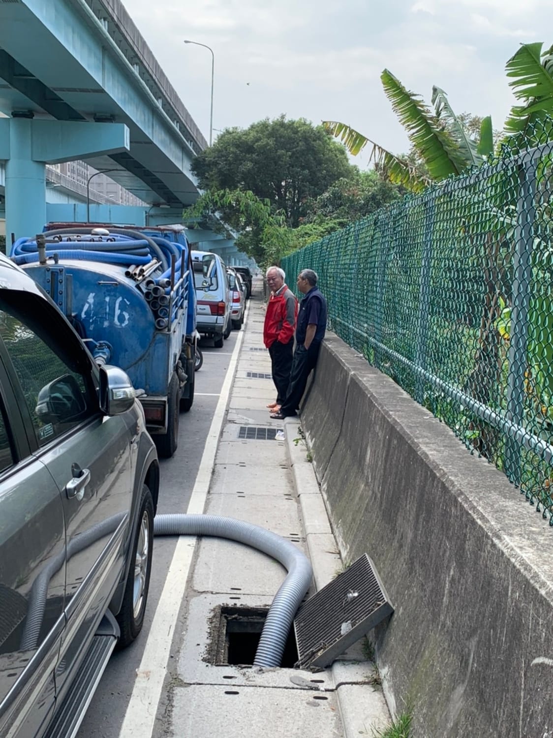 環保局稽查員及新莊分局員警埋伏發現業者將車輛停放在停車格，非法排放水肥於路邊。  圖：新北市環保局提供