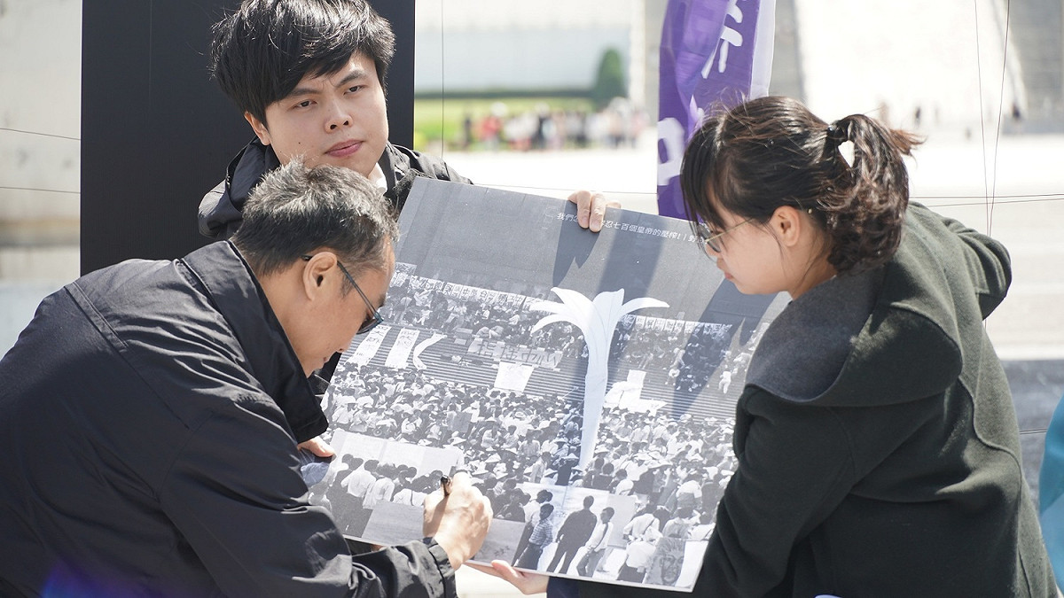當年首批赴自由廣場靜坐的野百合學生周克任（中）為當年的照片簽名。 圖：主辦單位提供