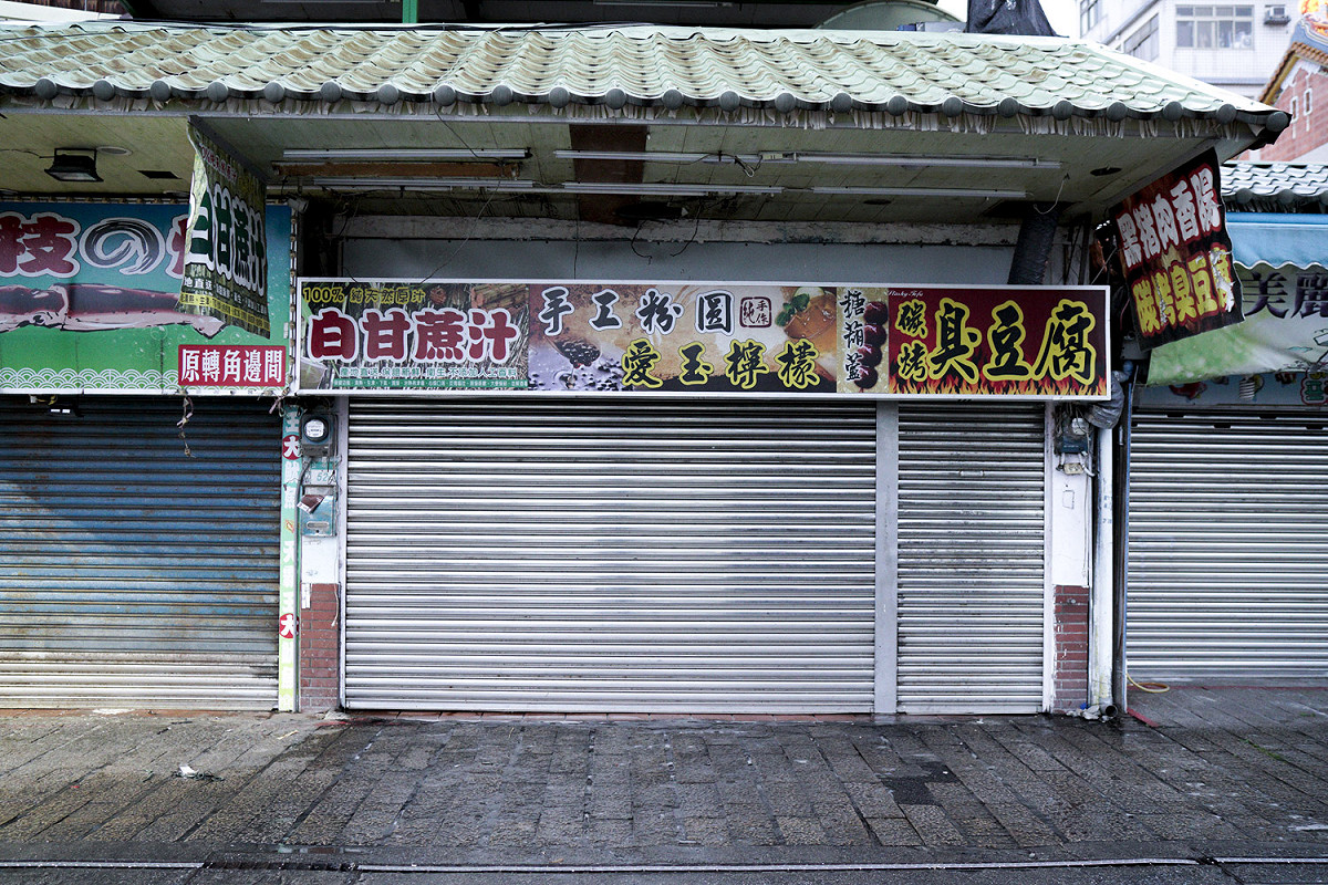 週一、下雨又偏逢武漢肺炎疫情，在淡水河邊營業的商家索性都拉下鐵門不營業。由於疫情持續不知何時結束，部份無法支撐的店家被迫結束營業止血。 圖：張良一/攝