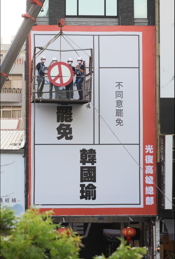 投票日期出爐，「罷韓四君子」乘坐吊籠升空，蓋上同意罷免章 ，宣布「50天民主搶灘開始」。 圖：翻攝Wecare高雄臉書