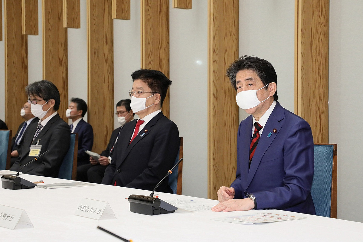 日本首相安倍晉三（右）22日出席記者會，戴的口罩尺寸明顯不合，只能勉強棄住口鼻。 圖：翻攝自日本首相官邸
