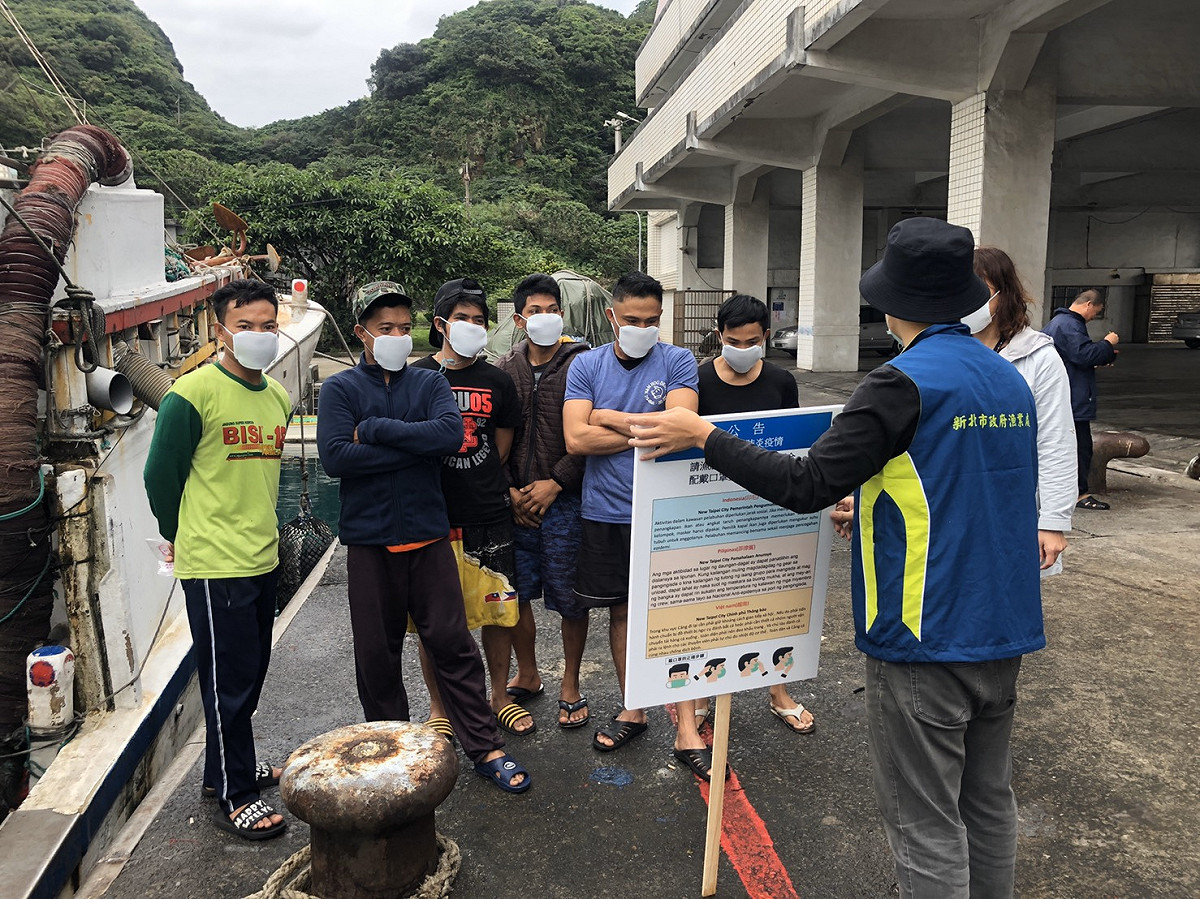 新北市漁業處人員在漁港手舉牌趴趴走，宣導漁船主及外籍漁民規定。 圖：新北市漁業處提供