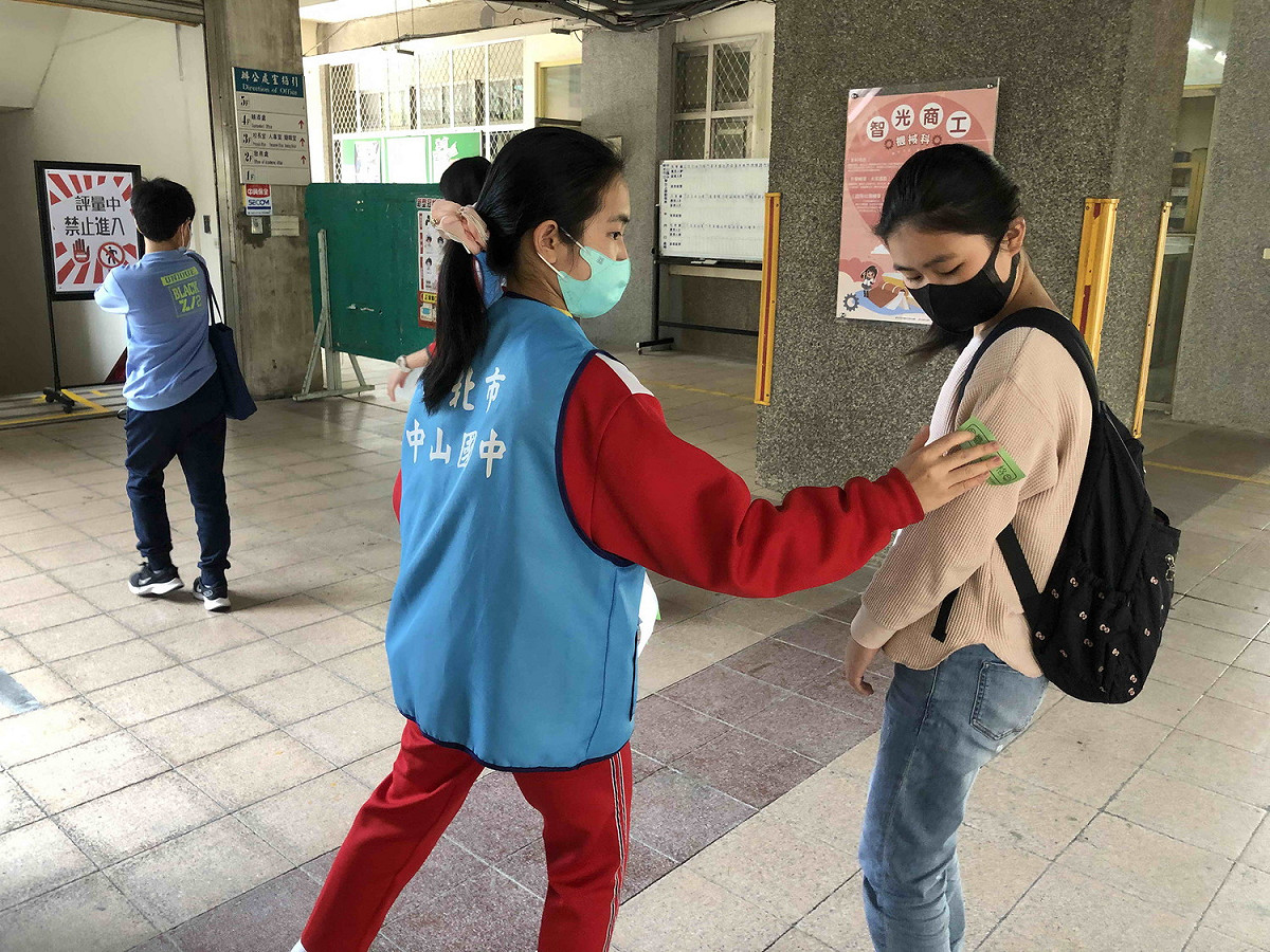 新北市國中學術資優鑑定複選評量，各試場由學生志工為考生量體 、張貼安全體溫貼紙。  圖：新北市教育局提供