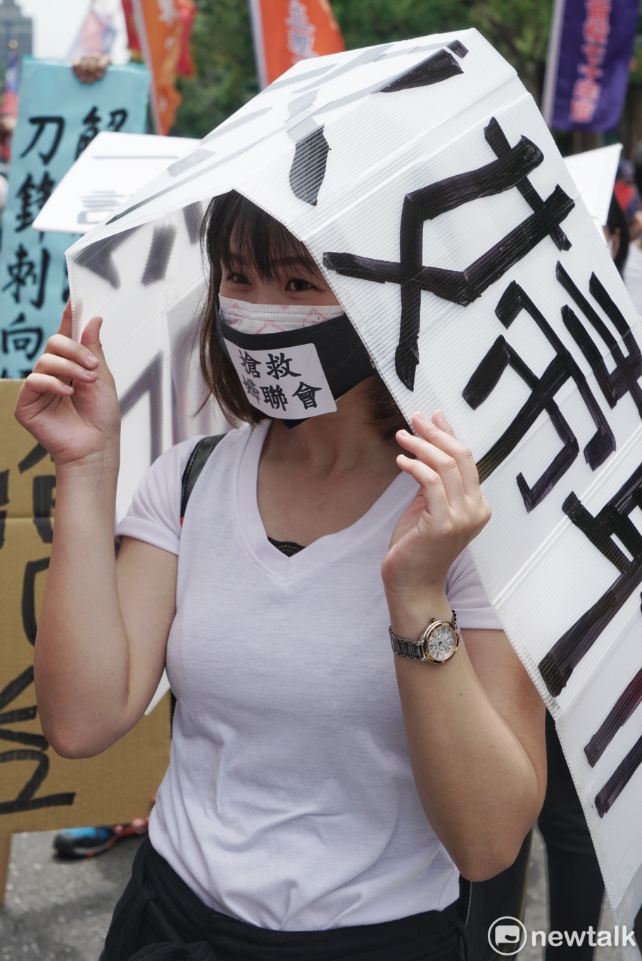 一位民眾戴口罩和寫著婦聯會的白色牌子聲援婦聯會。 圖：張良一/攝