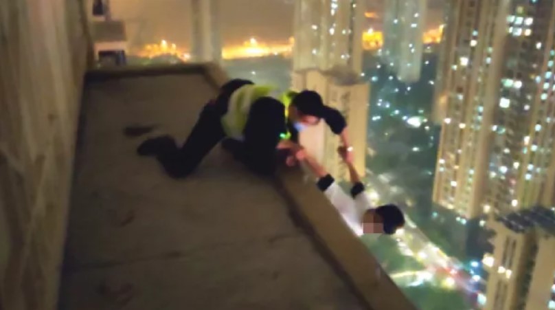 青年快要墜樓時，員警及時出手搭救。 圖：翻攝自新華社微信