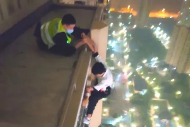 青年原本打算從34層樓高的地方跳下，所幸員警及時救援。 圖：翻攝自新華社微信