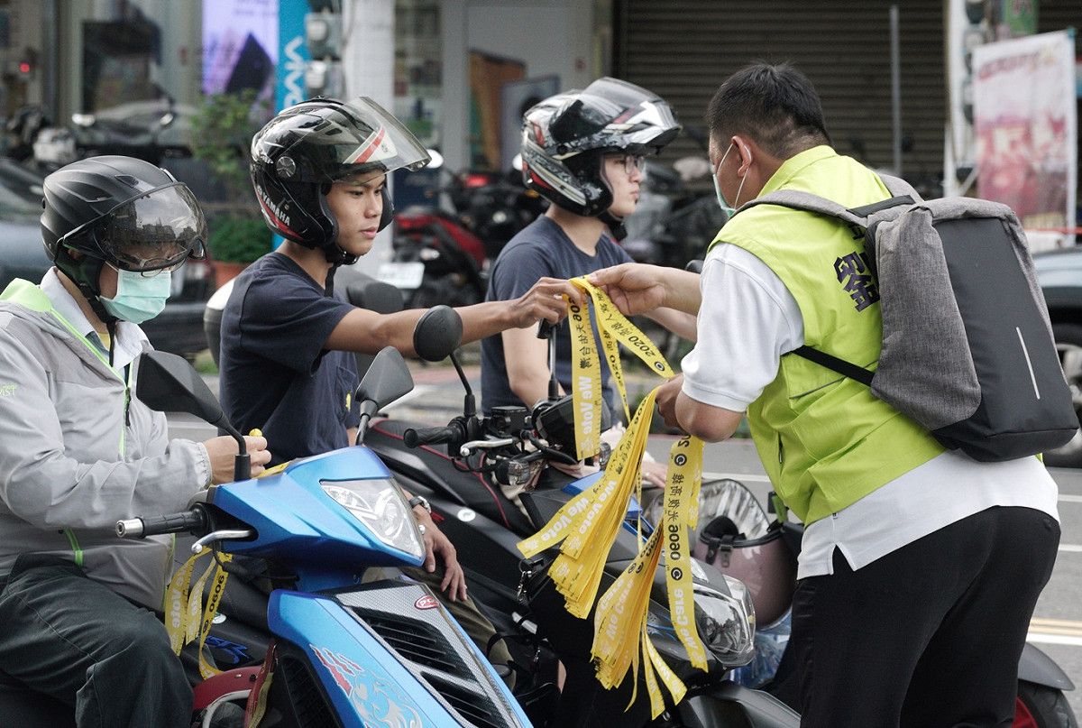 民進黨立委劉世芳的一位工作人員在楠梓火車站前發放罷韓黃絲帶。 圖：張良一/攝