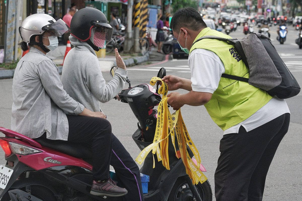 民進黨立委劉世芳的一位工作人員在楠梓火車站前發放罷韓黃絲帶，但是遭一位女騎士搖手婉拒。 圖：張良一/攝