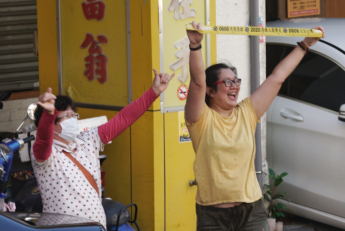 兩位市民，一位比出象徵罷韓的六號手勢，一位高舉罷韓黃絲帶向掃街車隊上的人員加油打氣。 圖：張良一/攝