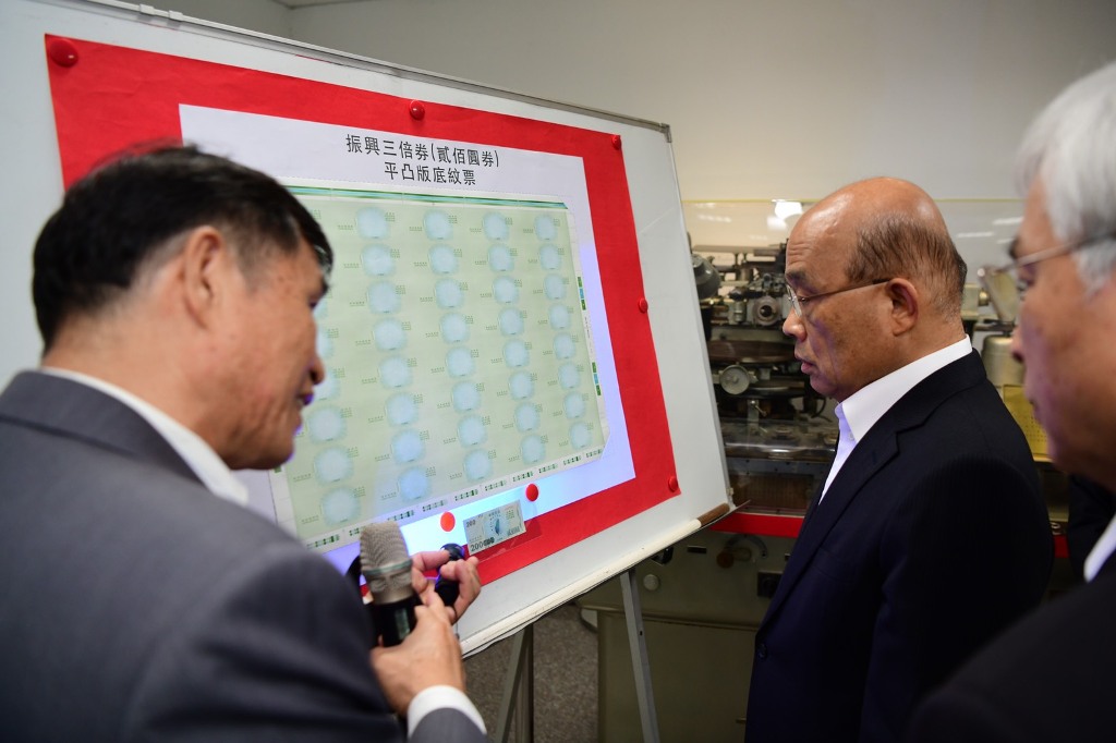 行政院長蘇貞昌仔細觀看三倍券半成品的平凸版底紋票。 圖：行政院提供