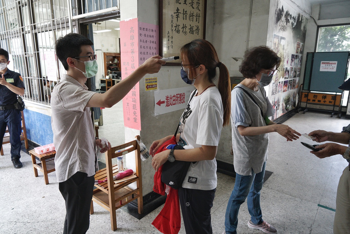 8點投票前，選務人員幫選民量體溫。。 圖：張良一/攝